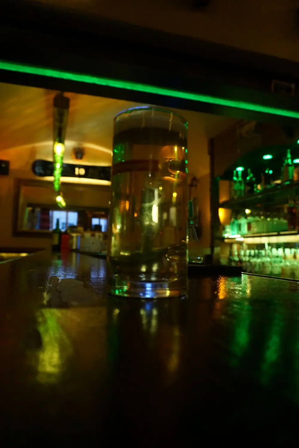 A full glass of beer on the counter in green light