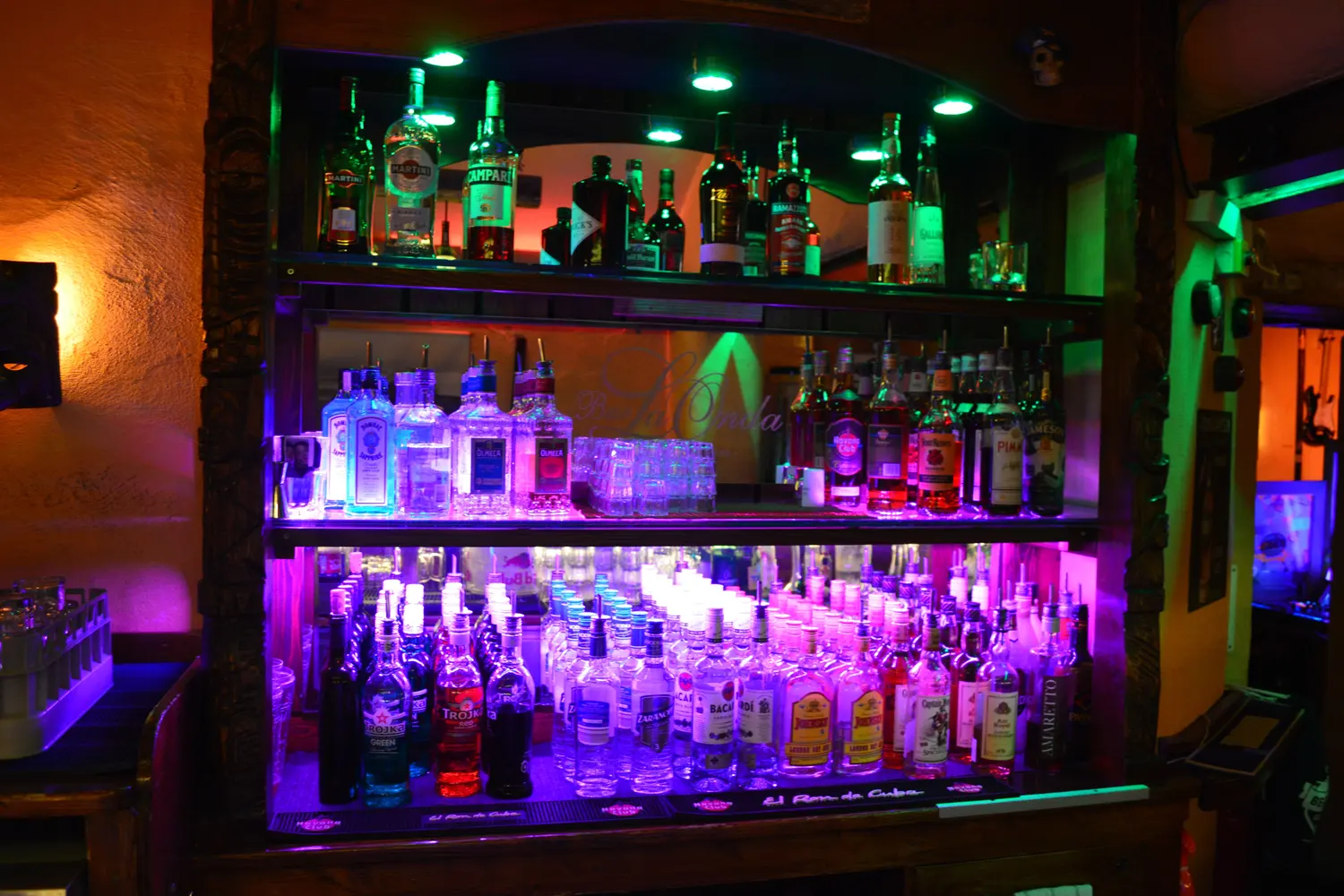 The lit shelf of bottles behind the counter