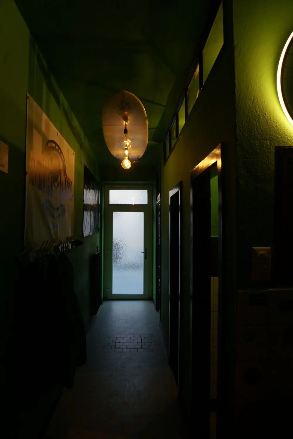 The dark corridor with a glass door at the end