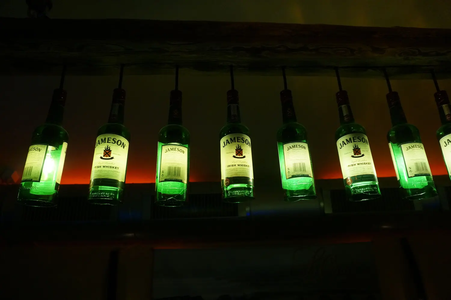 A row of green glowing Jameson bottles used as lamps