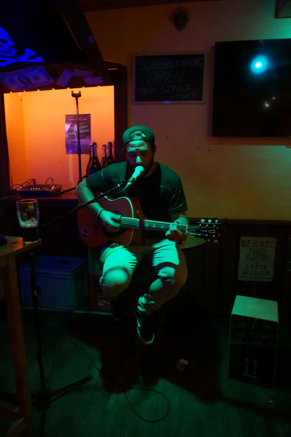 A musician sings and plays guitar in green light