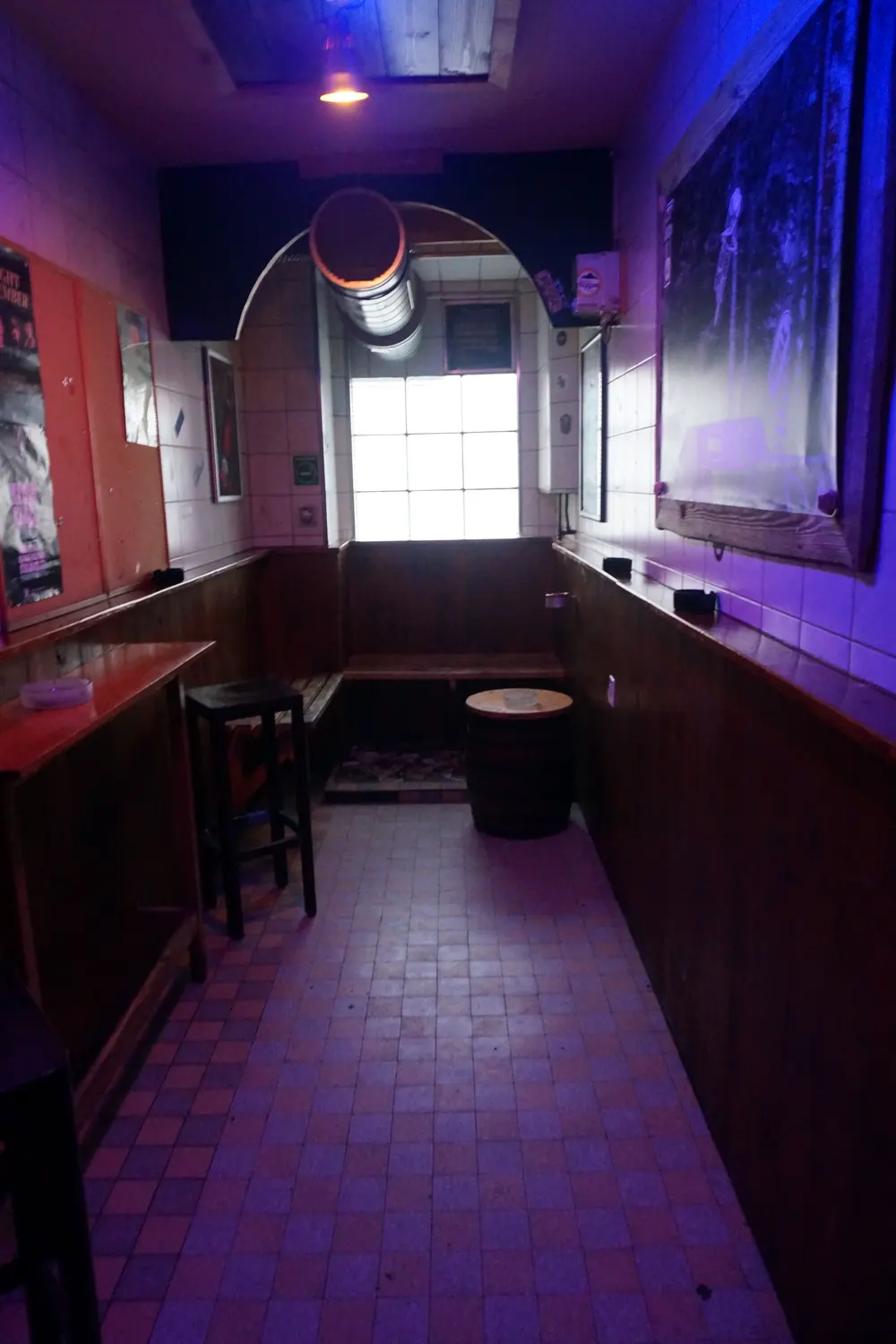 A small room with a wooden bench and a window in violet light