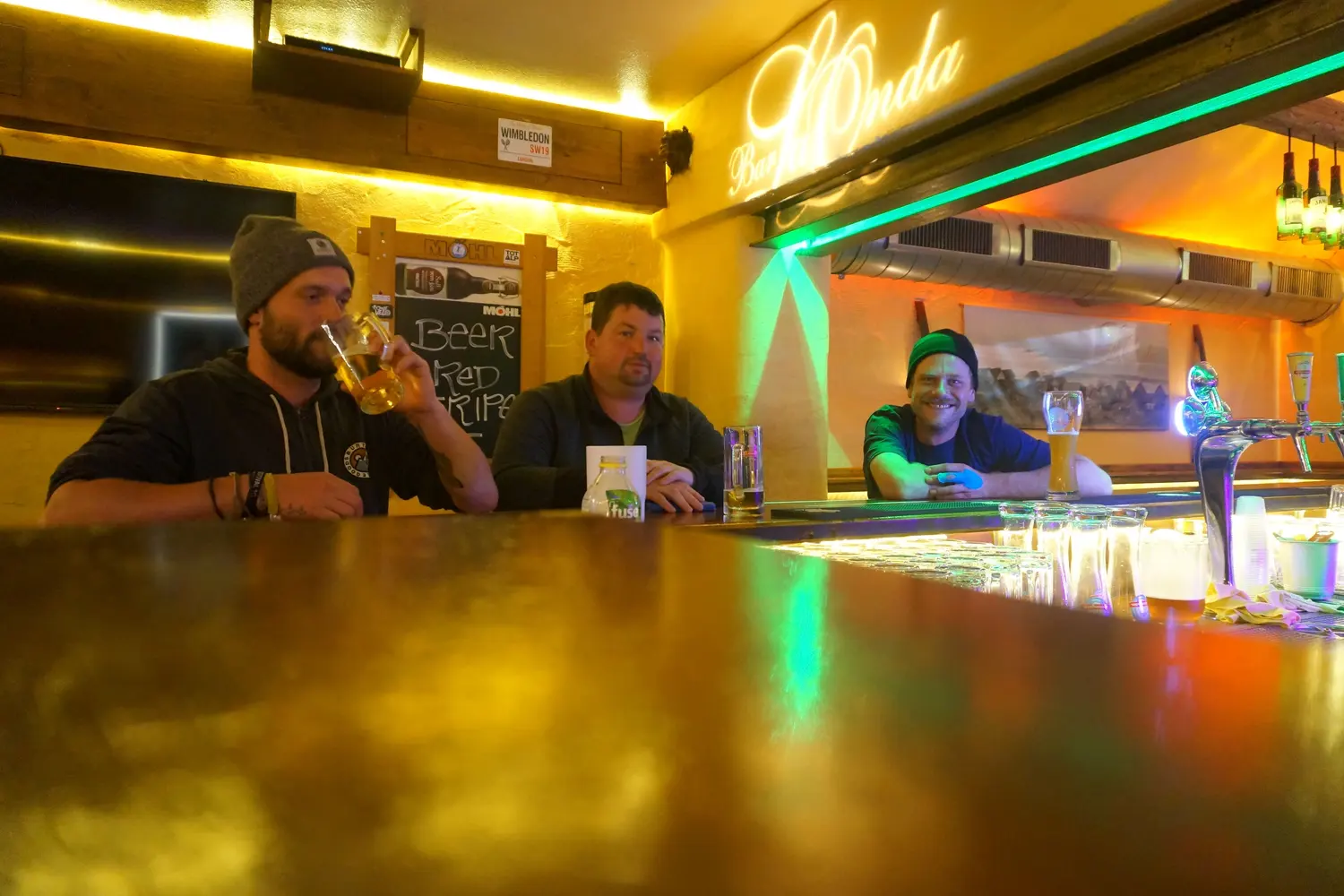 Three guests with beer at the shiny counter under the LaOnda lettering
